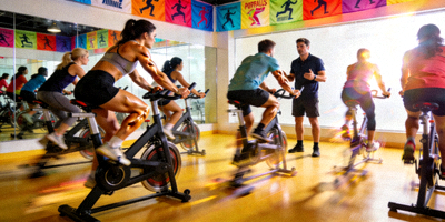 动感单车课程，学员在教练带领下进行室内骑行训练，充满活力